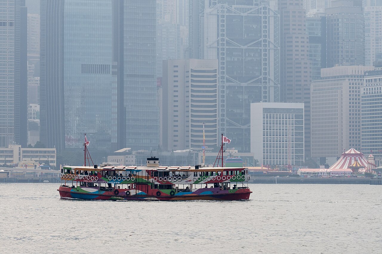 เรือ Star Ferry แล่นผ่านอ่าววิกตอเรียโดยมีอาคารฝั่งฮ่องกงอยู่ด้านหลัง