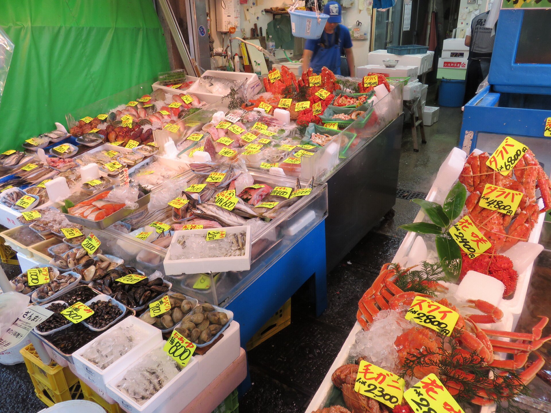 ร้านขายอาหารทะเลในตลาดสึกิจิ มีปู ปลา หอย และป้ายราคาภาษาญี่ปุ่น