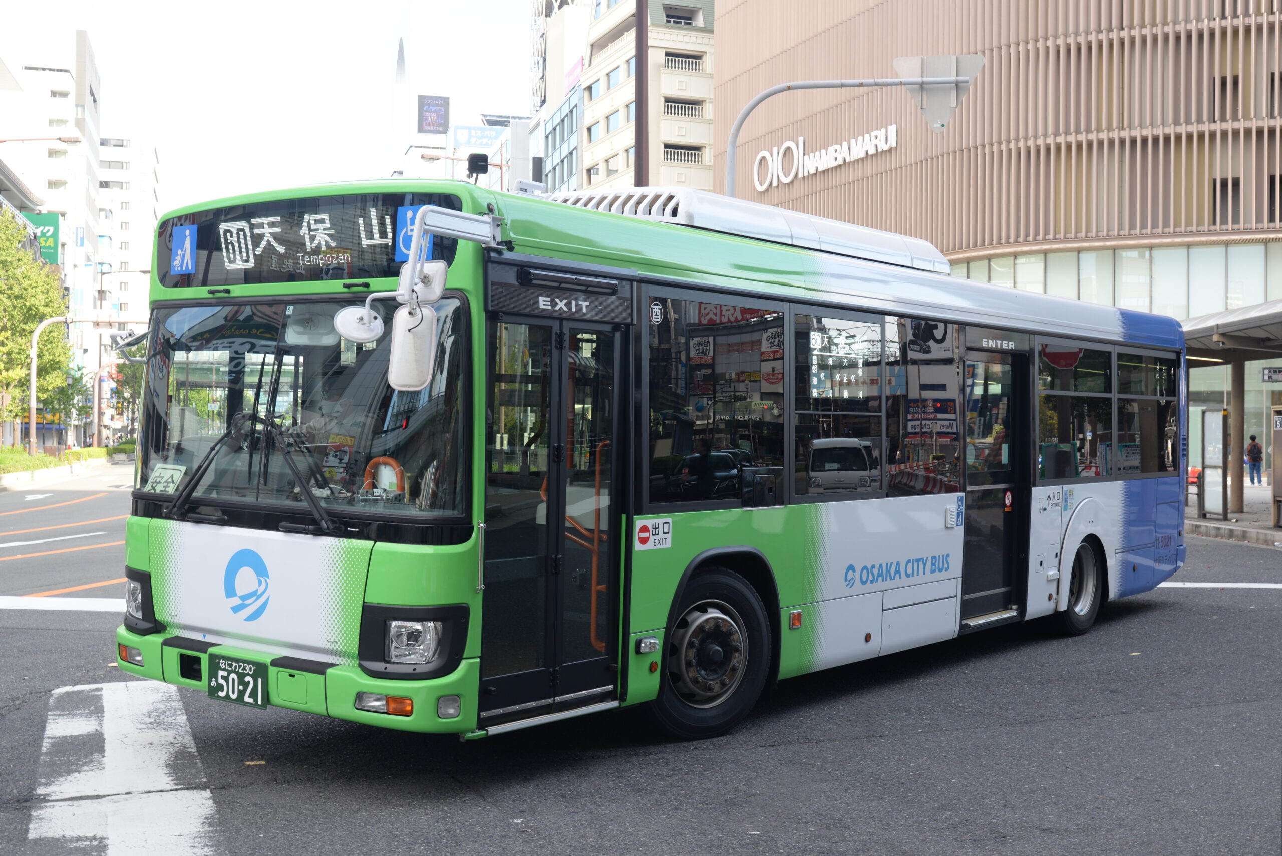 รถ Osaka City Bus สีเขียวและฟ้าจอดอยู่ในเมืองโอซาก้า