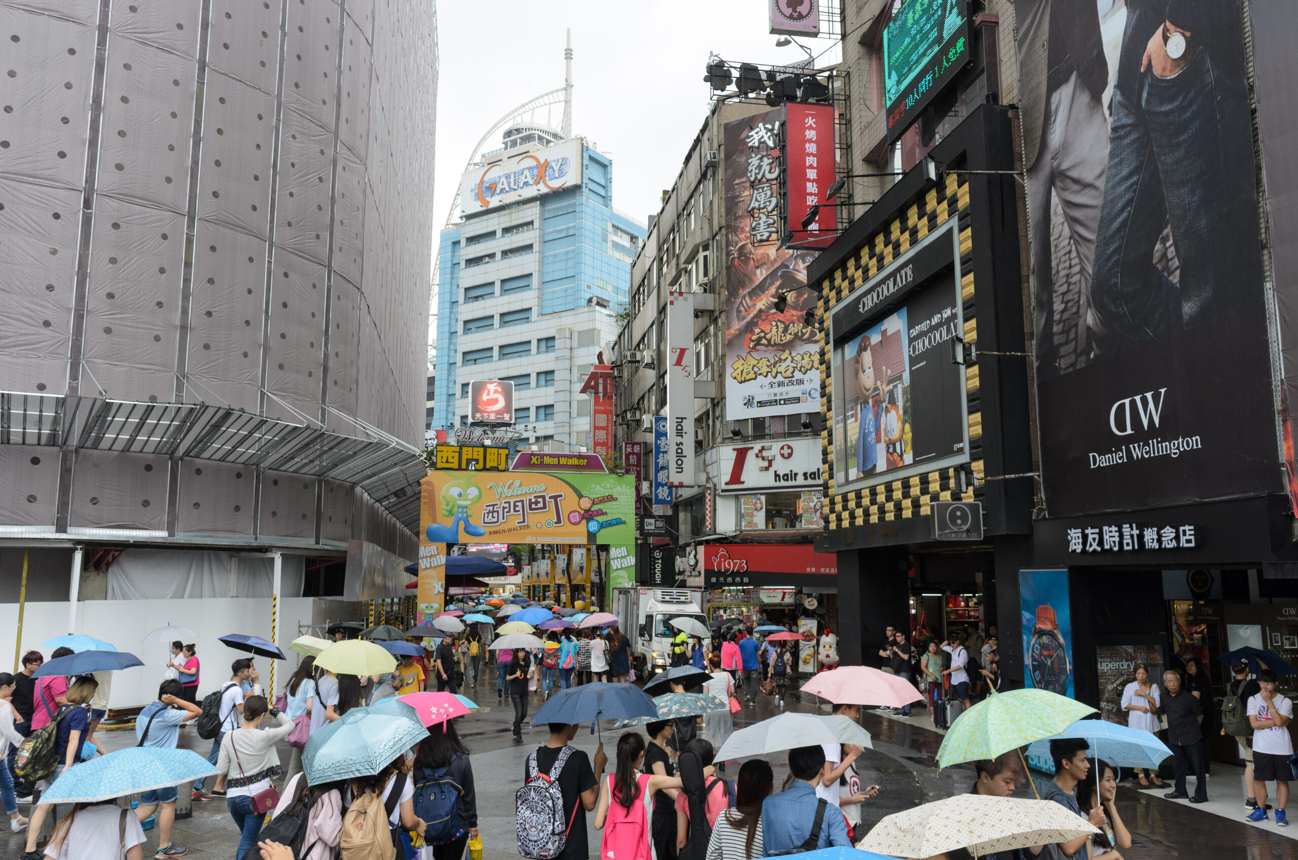 ผู้คนกางร่มเดินเข้าสู่ถนนฮั่นจงในไทเประหว่างฝนตก