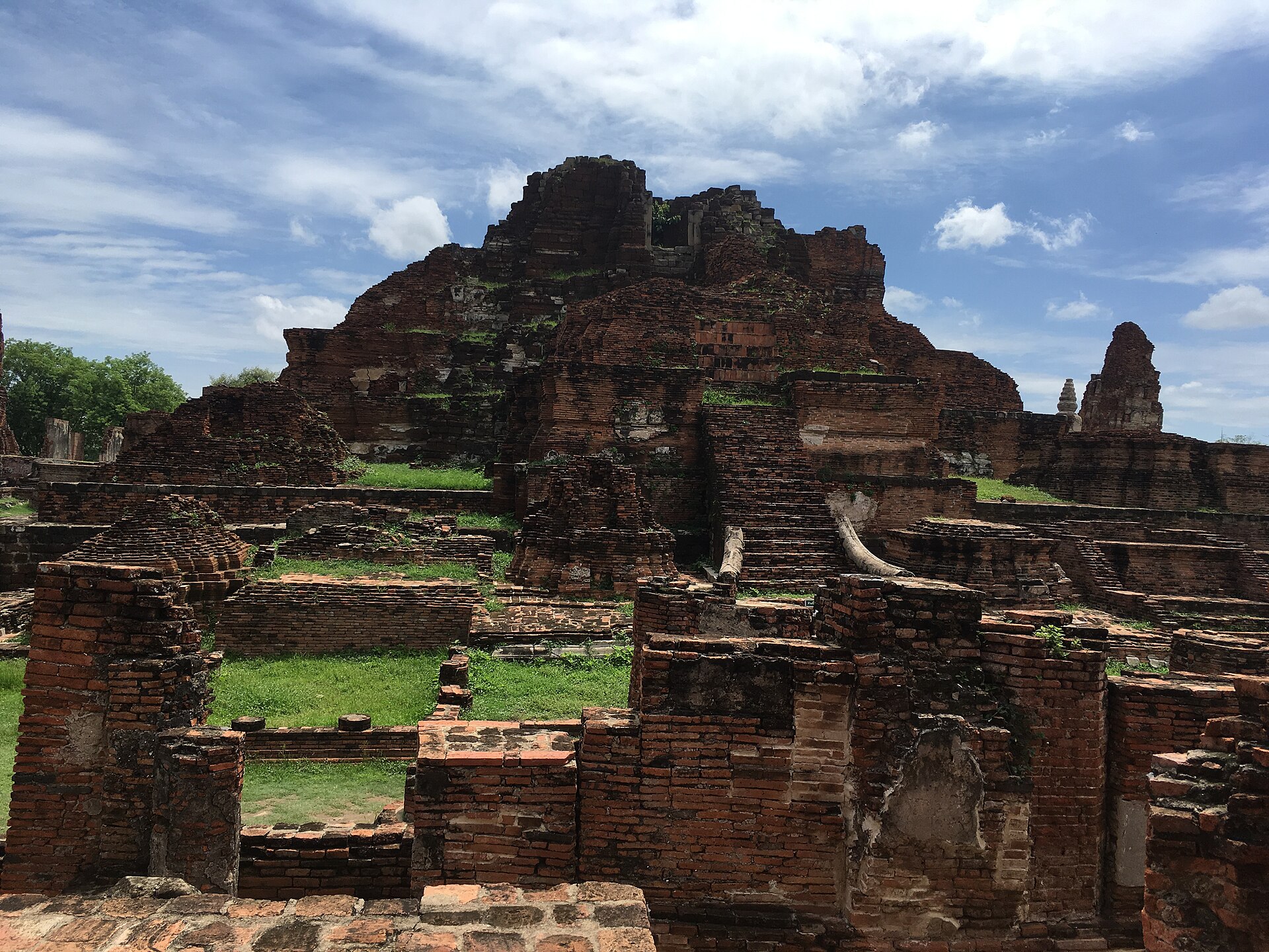 ซากอิฐวัดมหาธาตุในอุทยานประวัติศาสตร์พระนครศรีอยุธยา กลางวัน มีหญ้าและท้องฟ้า