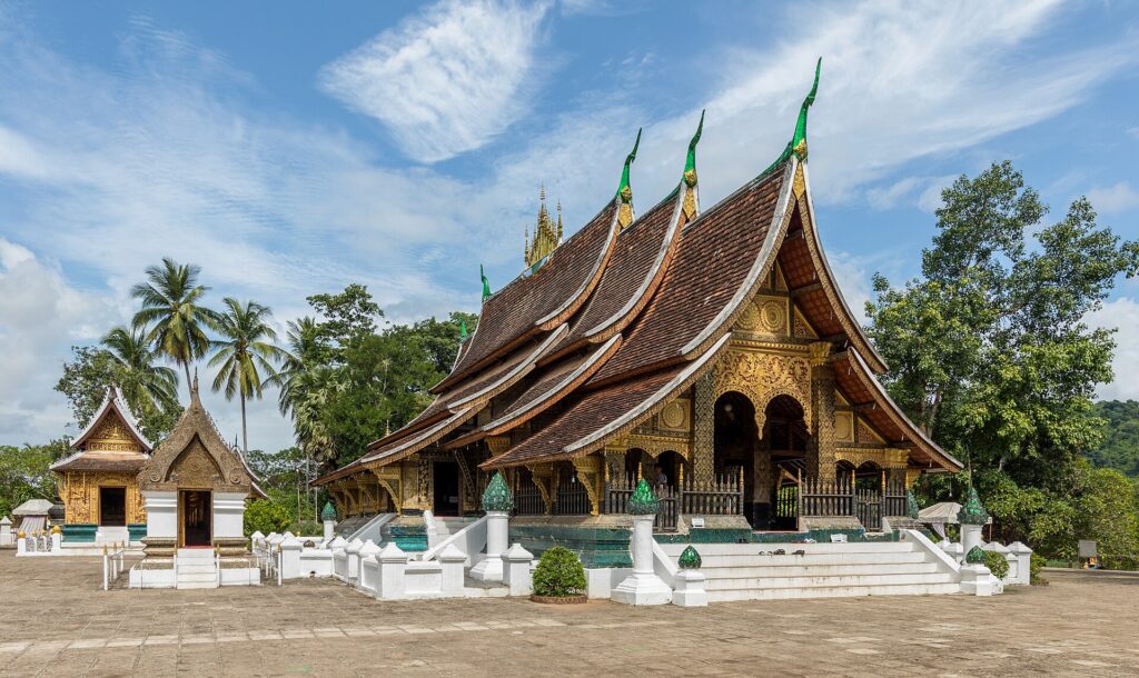 วัดเชียงทองหลวงพระบาง หลังคาสีหลายชั้นและหน้าบันทองในลานหินใต้ฟ้าสีฟ้า