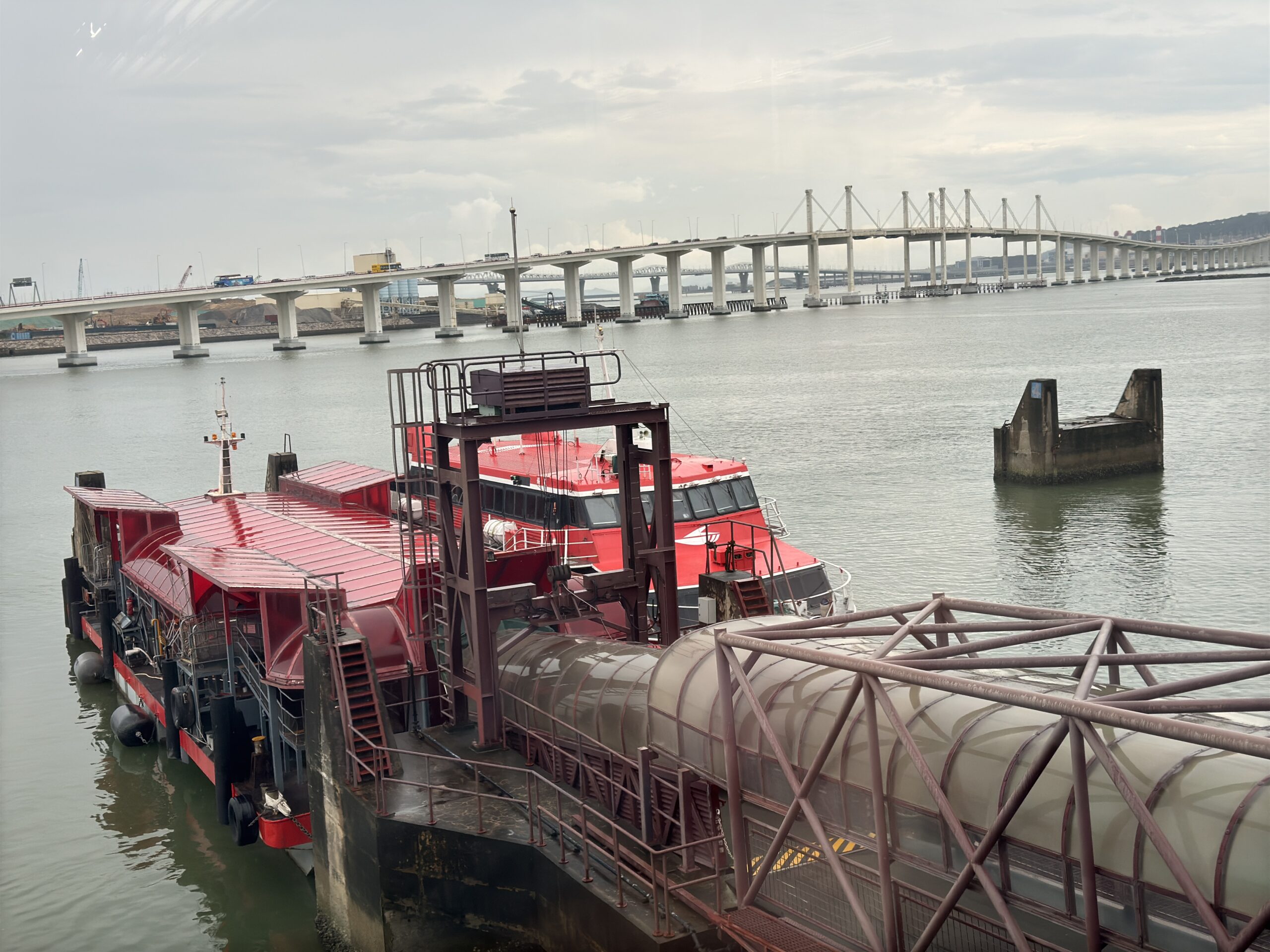 เรือเฟอร์รีแดงจอดท่าเอาท์เตอร์ฮาร์เบอร์พร้อมสะพานมิตรภาพด้านหลัง